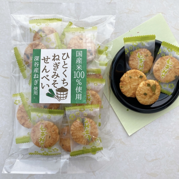 【ひとくちねぎみそせんべい】埼玉県深谷産の生ねぎを50％以上使用し、独自ブレンドの味噌だれを染み込ませ、バランスの取れた味付けとなっています。個包装でサクッとした食感も魅力です。